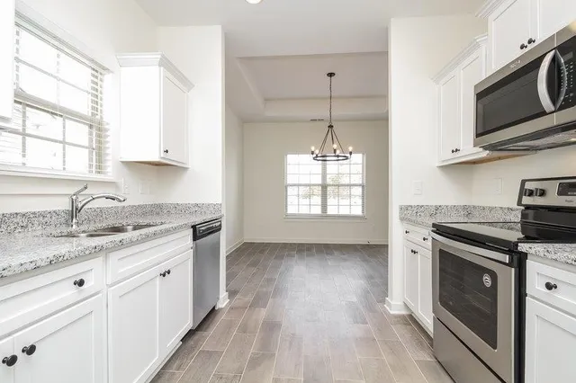 an empty room with chandelier fan and windows