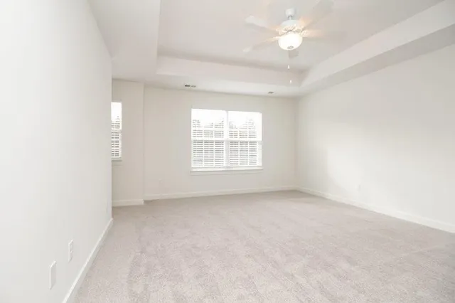 an empty room with chandelier fan and windows