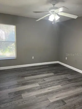 a view of an empty room with wooden floor and a window