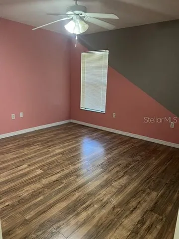 a view of an empty room with wooden floor and a window