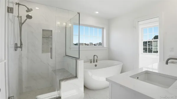 a bathroom with a tub sink shower and mirror