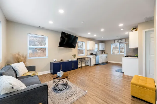 a living room with furniture flat screen tv and kitchen view