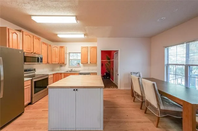a kitchen with stainless steel appliances granite countertop a refrigerator a stove a sink dishwasher with a dining table and chairs with wooden floor