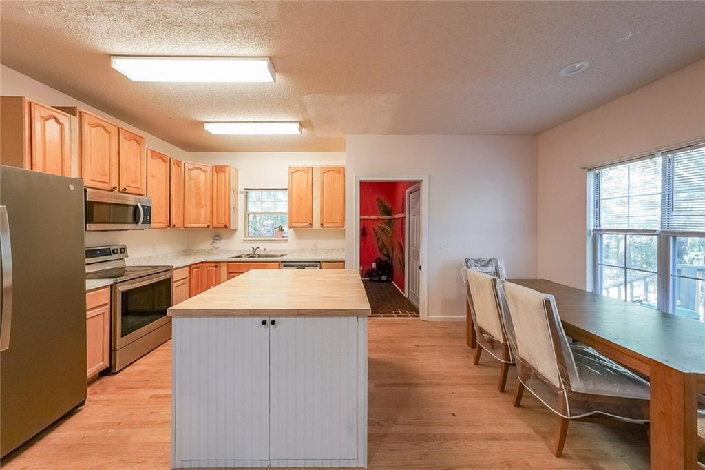 6554 Fox Run Winston, GA 30187 - Photo 7 of 40 a kitchen with stainless steel appliances granite countertop a refrigerator a stove a sink dishwasher with a dining table and chairs with wooden floor
