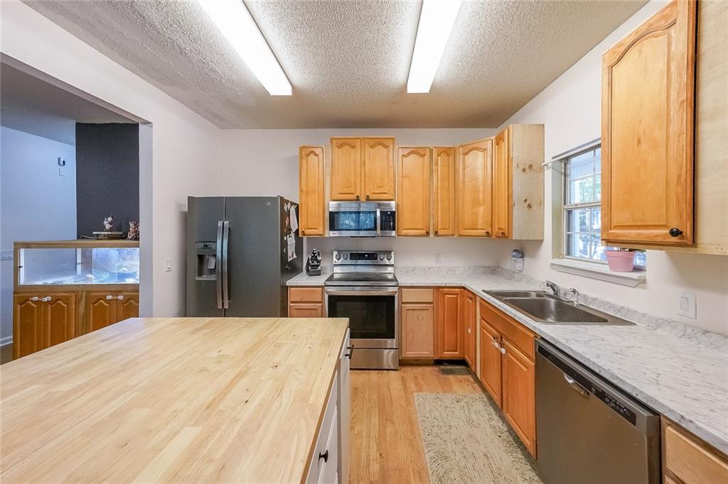 6554 Fox Run Winston, GA 30187 - Photo 10 of 40 a kitchen with a refrigerator a sink dishwasher a stove with cabinets and wooden floor