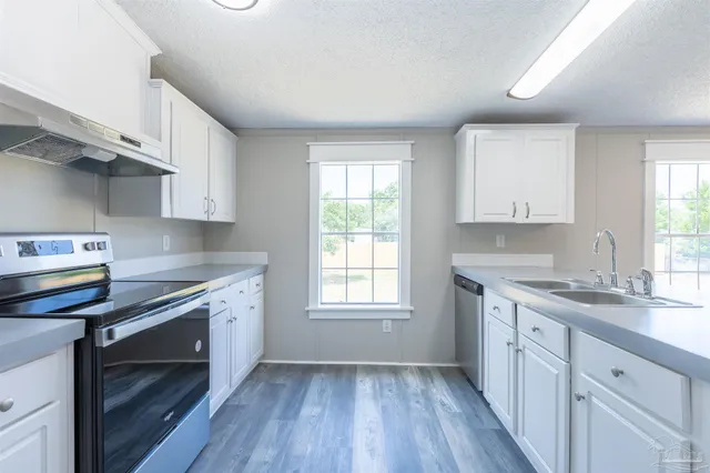a kitchen with a sink cabinets wooden floor and a window