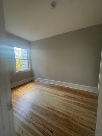 a view of an empty room with window and wooden floor