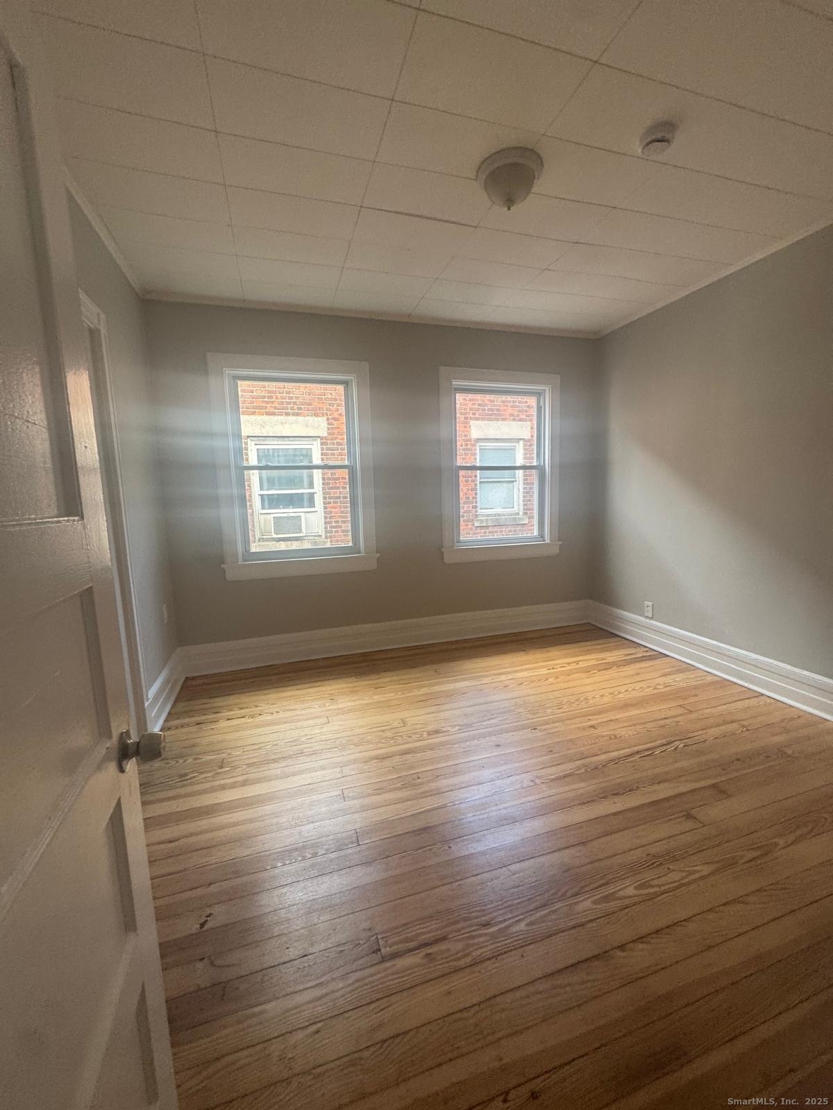 287 Dover Street, Unit 2 Bridgeport, CT 06610 - Photo 4 of 6 an empty room with wooden floor and windows
