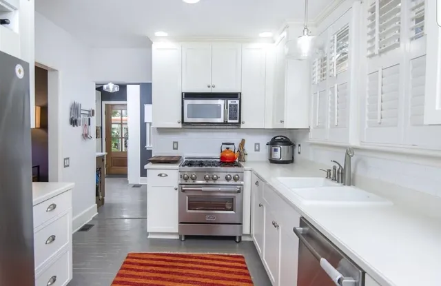 a kitchen with stainless steel appliances a stove a sink cabinets and a refrigerator