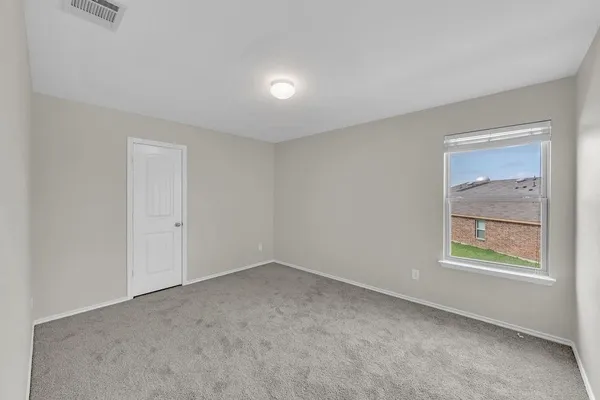 a view of an empty room with closet and a window