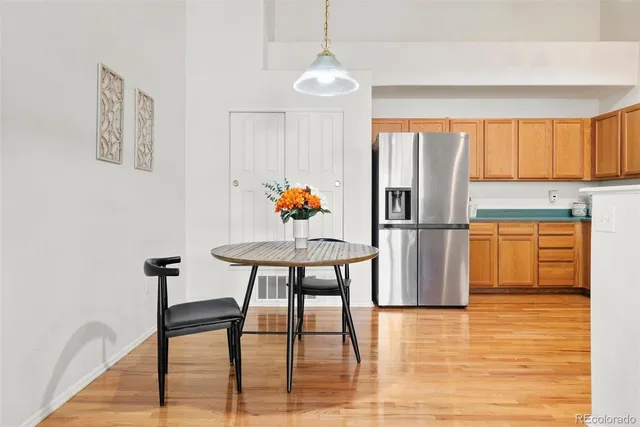 a kitchen with stainless steel appliances granite countertop a dining table chairs and a refrigerator
