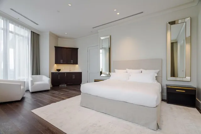 a bedroom with a bed couch and windows