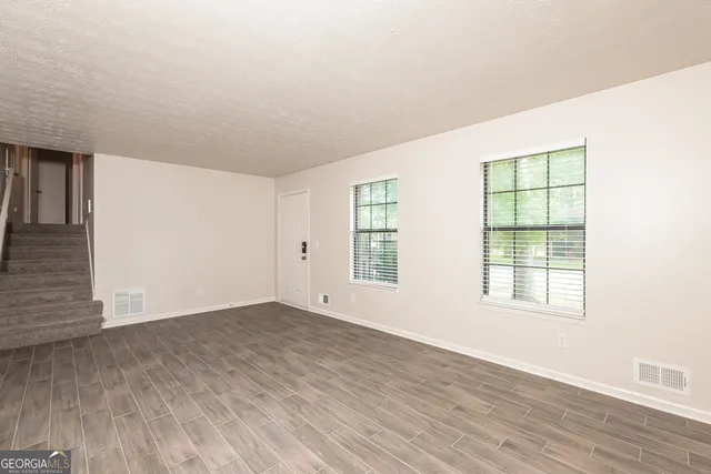 an empty room with wooden floor and windows