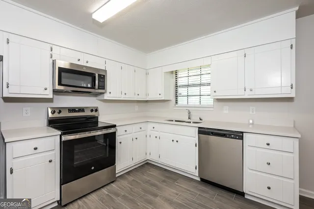 a kitchen with white cabinets white stainless steel appliances and sink