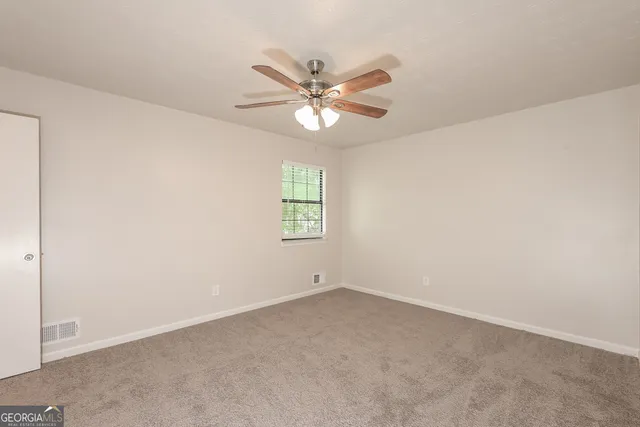 an empty room with a window and a fan
