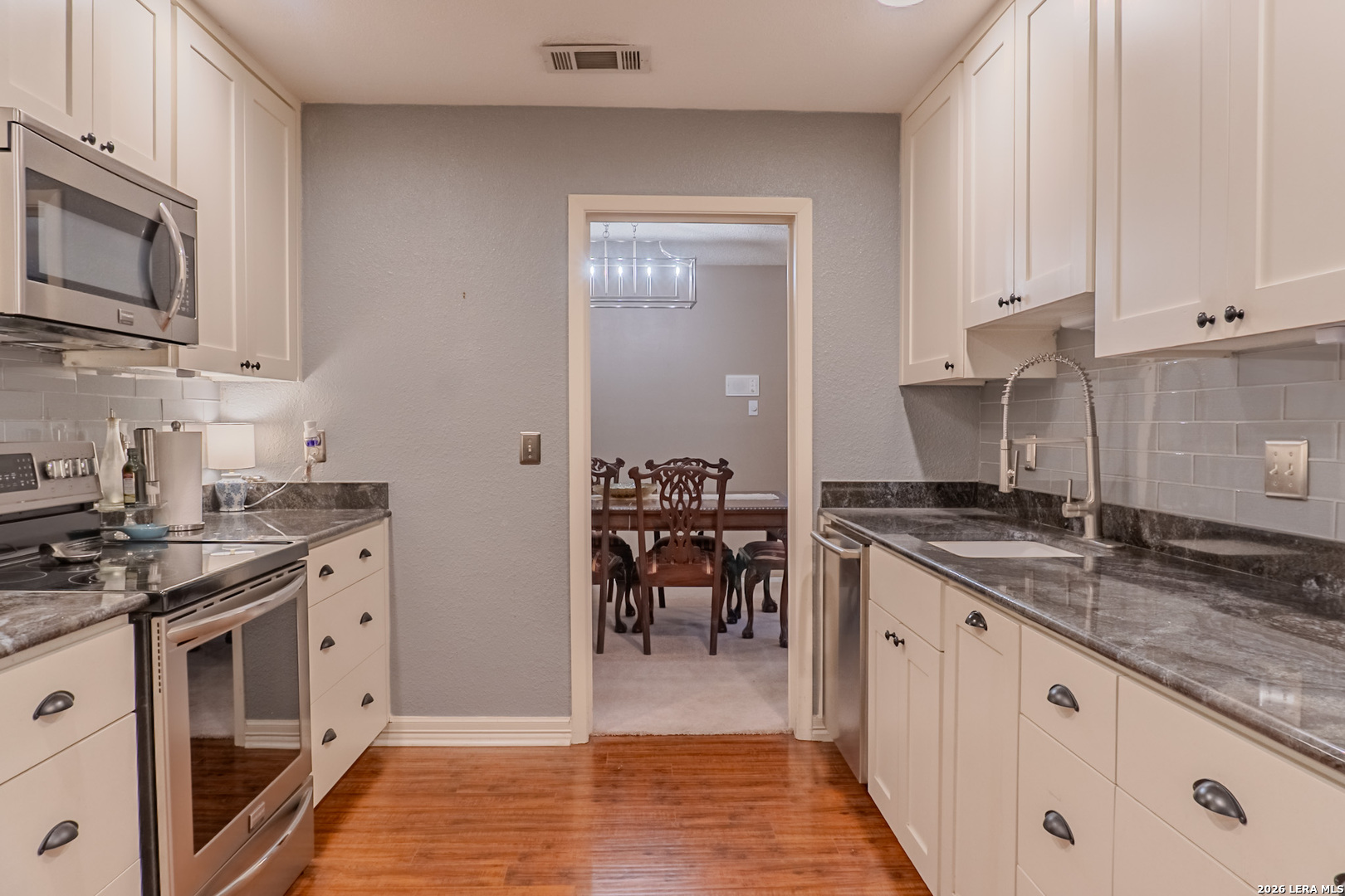 8942 Willmon Way Windcrest, TX 78239 - Photo 23 of 44 a kitchen with stainless steel appliances granite countertop a stove a sink and a microwave