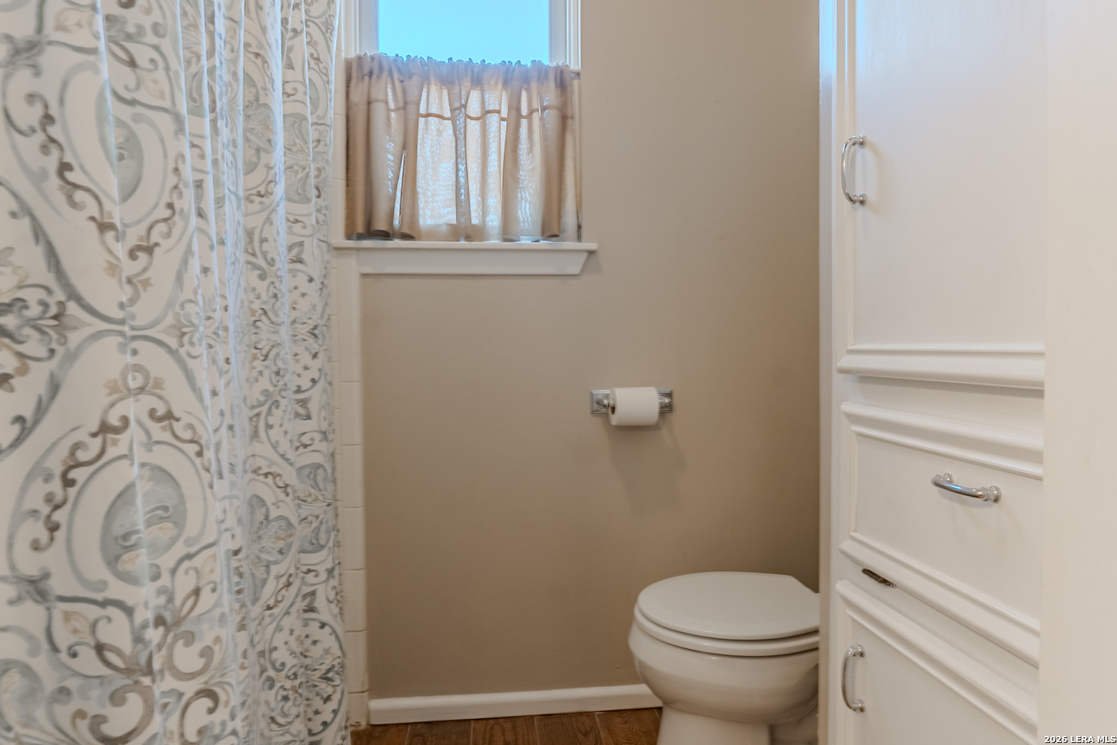 8942 Willmon Way Windcrest, TX 78239 - Photo 32 of 44 a white toilet sitting next to a shower curtain