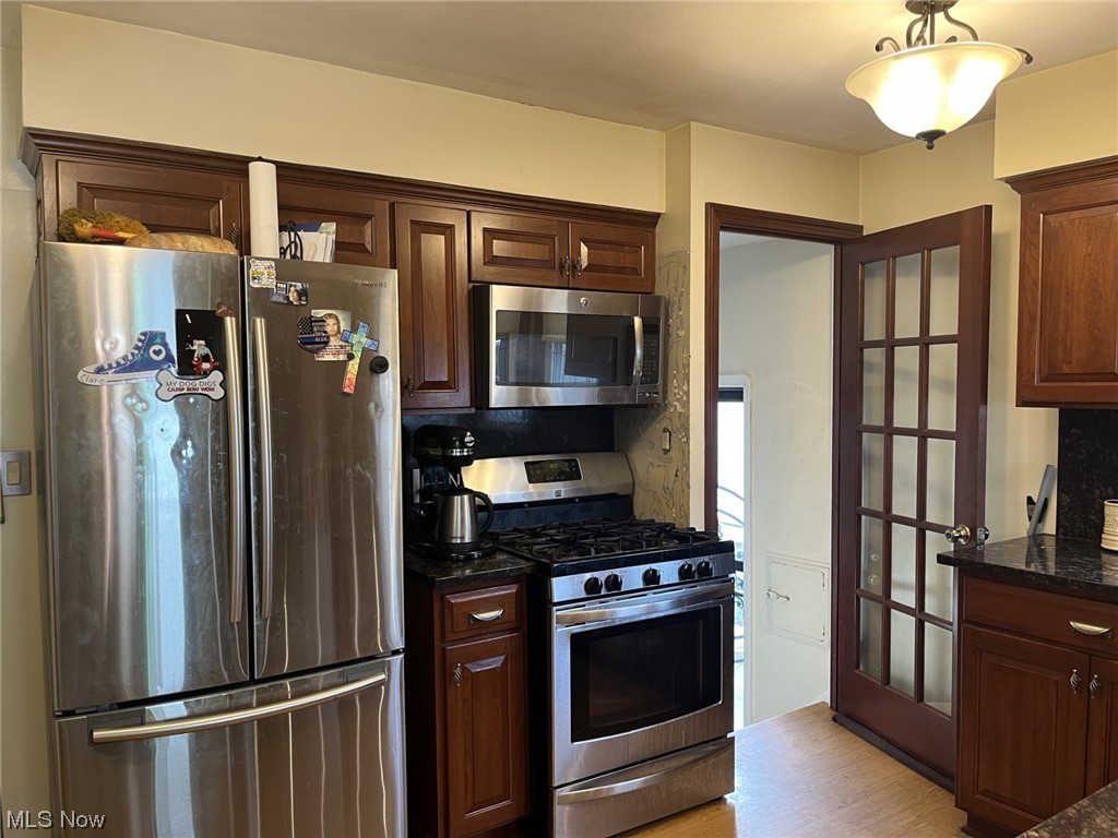 15705 Rockside Road Maple Heights, OH 44137 - Photo 10 of 37 Kitchen featuring dark brown cabinetry, light wood-style floors, stainless steel refrigerator, gas stove and microwave.