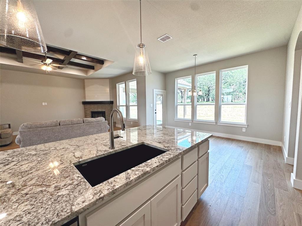 1005 Ronnie Court Springtown, TX 76082 - Photo 14 of 27 Kitchen island with a light-toned granite countertop and an undermount sink