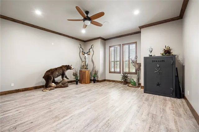 a view of an empty room with wooden floor and a chandelier fan