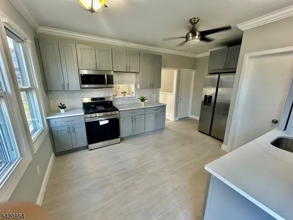 a kitchen with stainless steel appliances a refrigerator a sink a stove a microwave a sink a refrigerator and cabinets