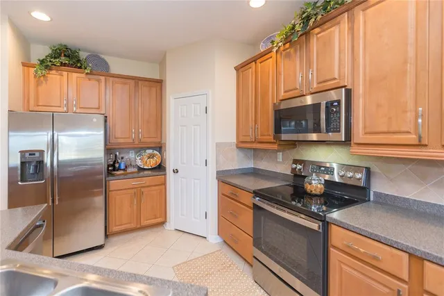 a kitchen with stainless steel appliances granite countertop a refrigerator a sink a stove a microwave and cabinets