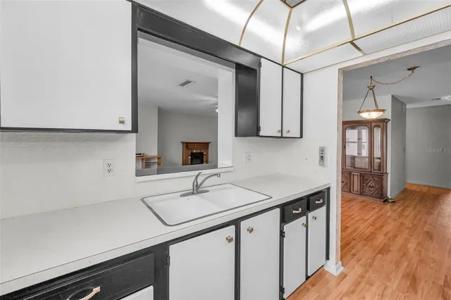 a view of a white house in front of a big yard with plants and large trees