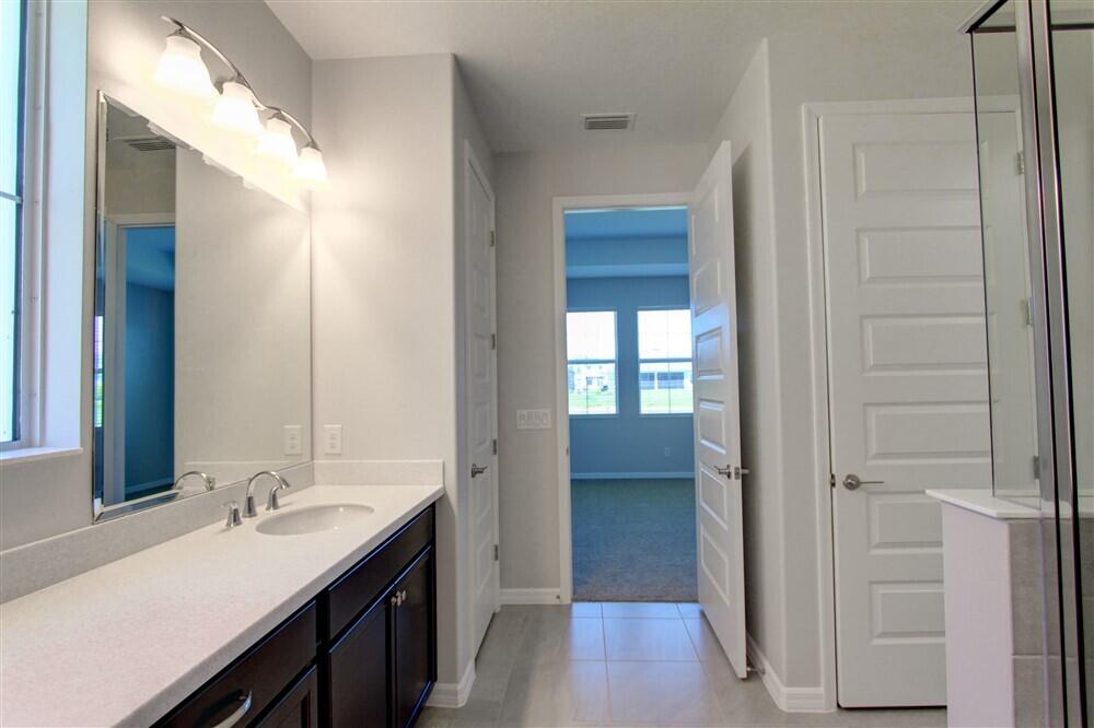 2508 Pangea Circle Melbourne, FL 32940 - Photo 16 of 34 a en suite bathroom with a granite countertop sink and a mirror