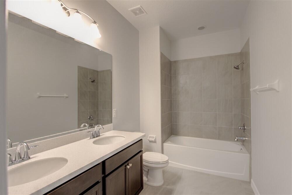 2508 Pangea Circle Melbourne, FL 32940 - Photo 19 of 34 a bathroom with a bathtub shower sink vanity mirror and toilet