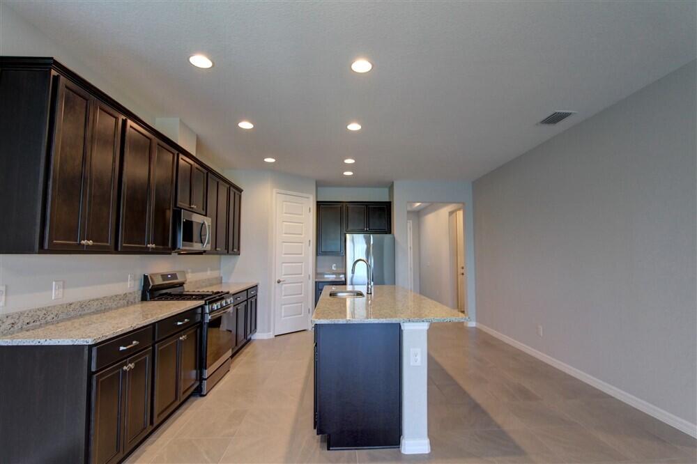 2508 Pangea Circle Melbourne, FL 32940 - Photo 25 of 34 a kitchen with stainless steel appliances granite countertop a refrigerator and a stove top oven