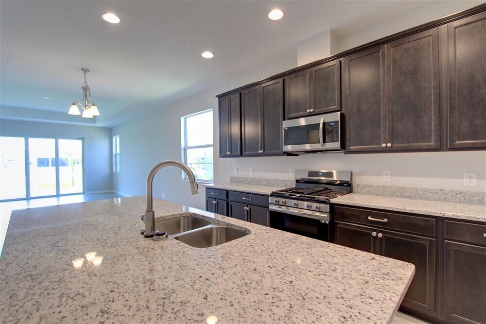 2508 Pangea Circle Melbourne, FL 32940 - Photo 9 of 34 a kitchen with kitchen island granite countertop a stove and a sink with cabinets