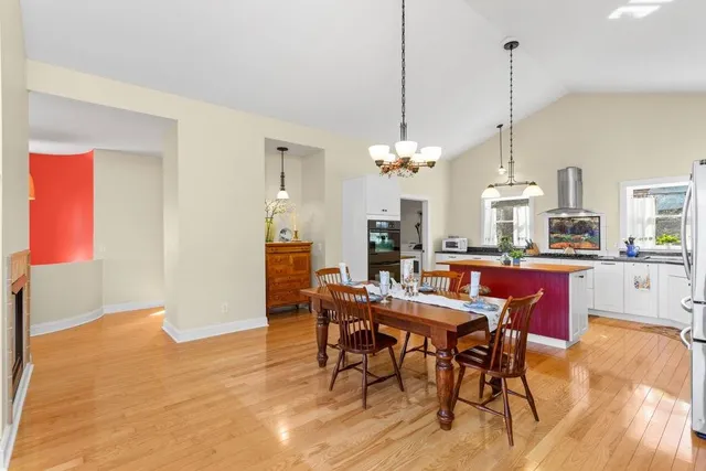 a view of a dining room and livingroom with furniture wooden floor a rug a chandelier and a view