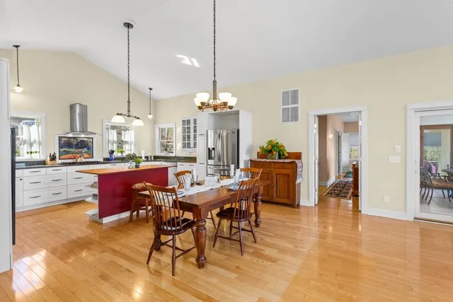a view of a dining room and livingroom with furniture wooden floor a chandelier