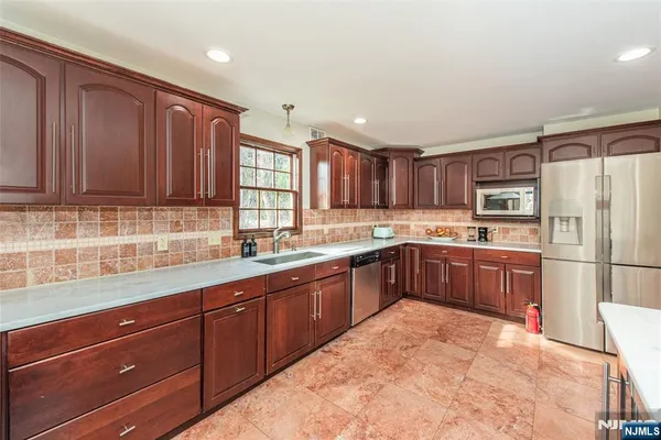 a kitchen with stainless steel appliances granite countertop a refrigerator and wooden cabinets