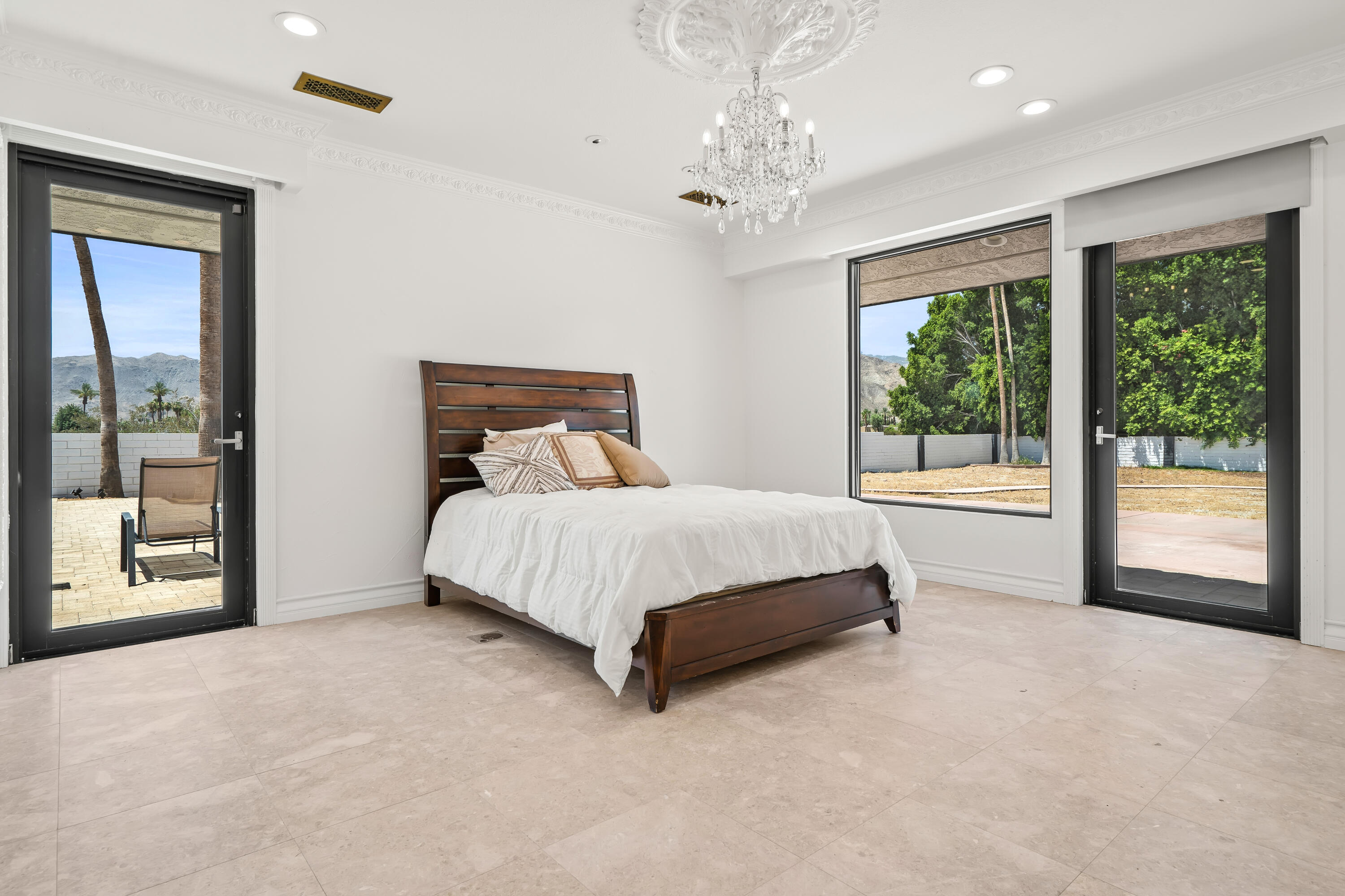 401 Iris Lane Rancho Mirage, CA 92270 - Photo 34 of 87 a bed sitting in a spacious bedroom next to a window and a chandelier