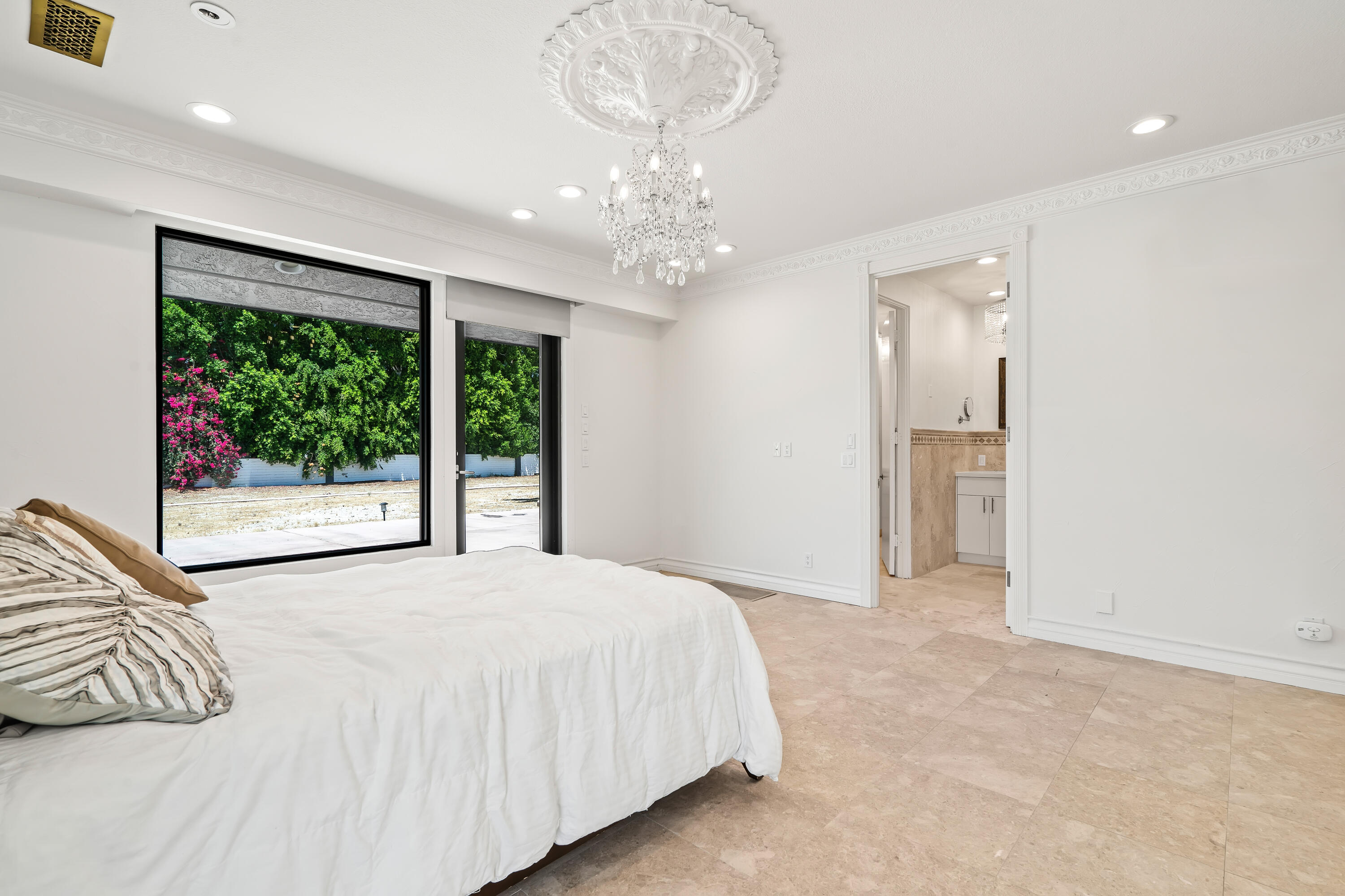 401 Iris Lane Rancho Mirage, CA 92270 - Photo 39 of 87 a spacious bedroom with a bed and a chandelier