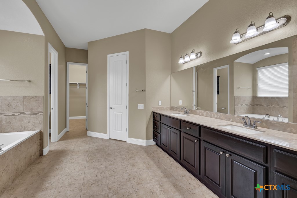 2194 Ranch Loop Drive New Braunfels, TX 78132 - Photo 16 of 48 a spacious bathroom with a double vanity sink a large mirror and a bathtub