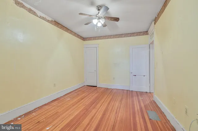 a view of a room with wooden floor and a ceiling fan