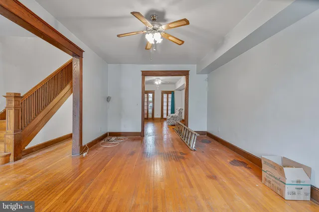 a view of an empty room with wooden floor and a ceiling fan