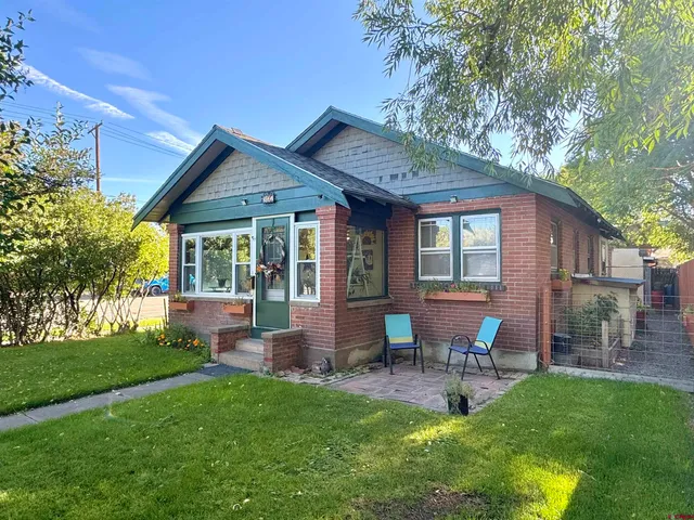 a view of a house with a yard and a large tree