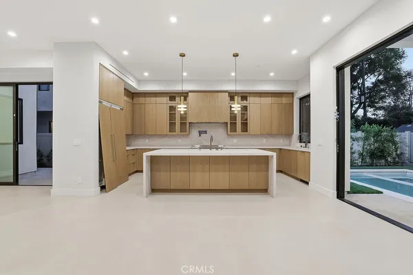 a view of an empty room with kitchen and a sink