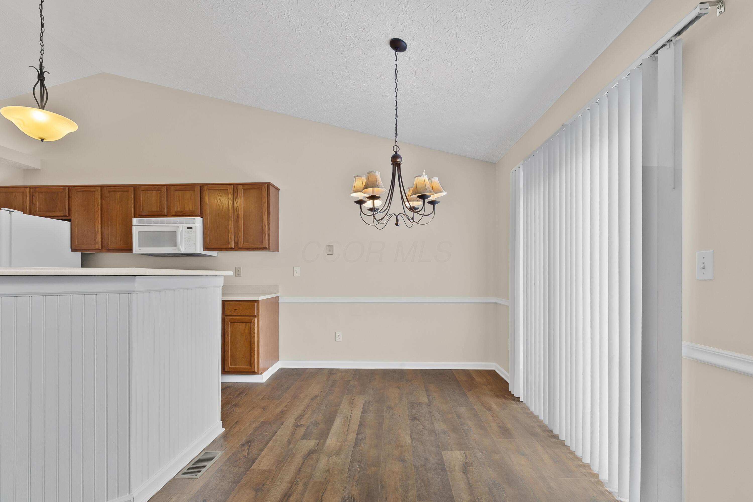 30 Tabilore Loop Delaware, OH 43015 - Photo 23 of 55 • New luxury vinyl plank flooring ~ 2025 • Tan painted walls • Chair railing • Chandelier • Vaulted ceiling • Sliding doors to deck • Vertical blinds