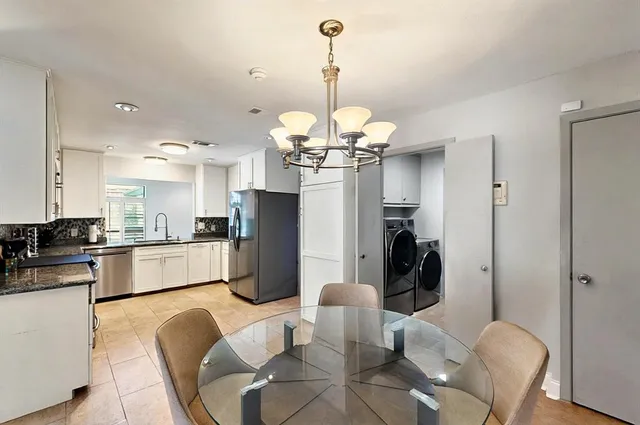 a kitchen with stainless steel appliances kitchen island granite countertop a refrigerator a stove a microwave oven a dining table and chairs with wooden floor