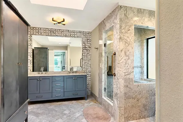 a spacious bathroom with a granite countertop sink a mirror and shower