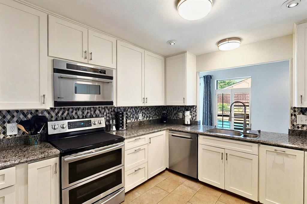 7109 Alpha Road Dallas, TX 75240 - Photo 10 of 36 a kitchen with granite countertop white cabinets and stainless steel appliances