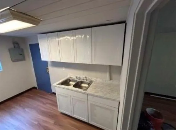 a kitchen with a white cabinets and wooden floor