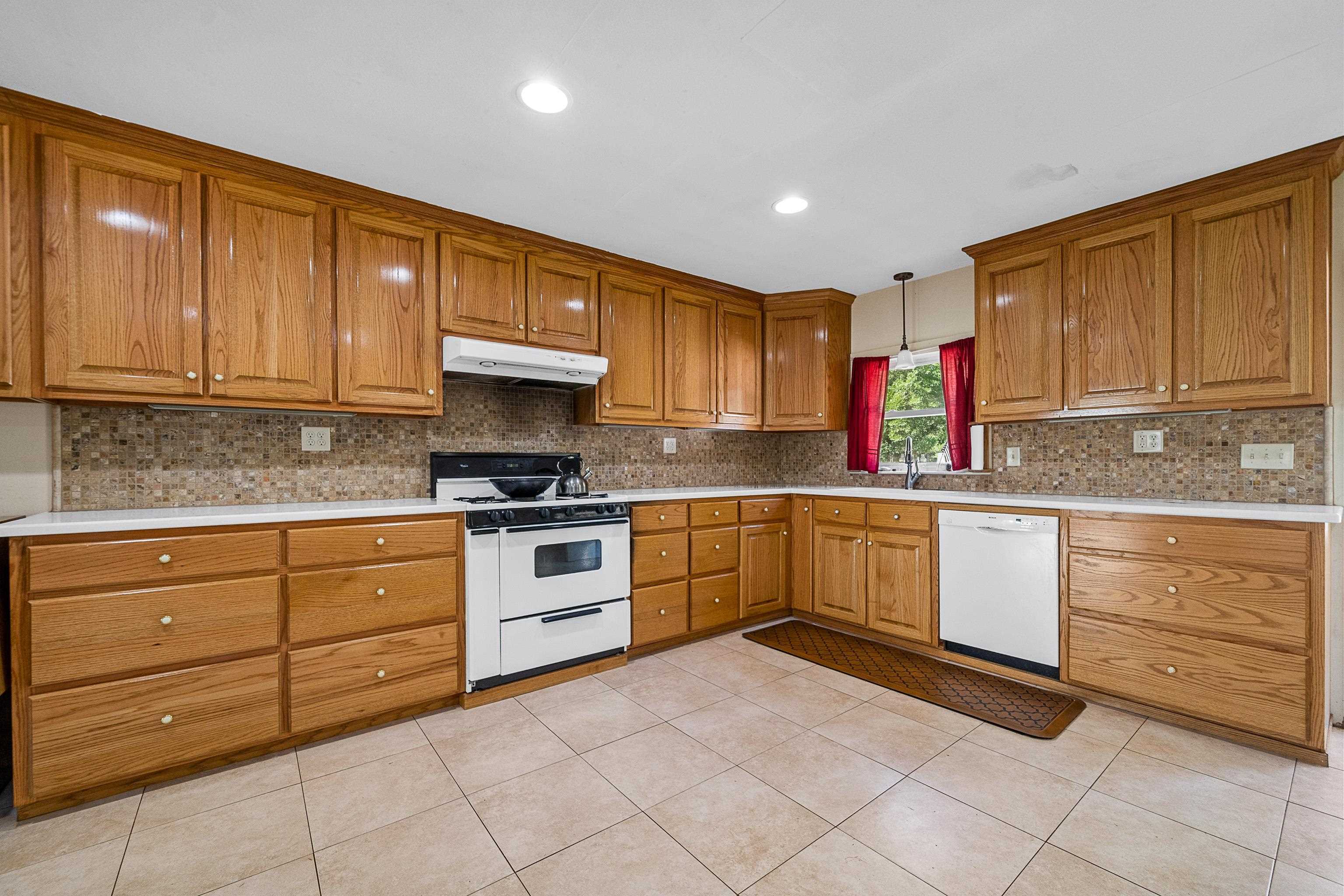 9350 Tompkins Road Stockton, AL 36579 - Photo 26 of 36 Kitchen featuring brown cabinets, backsplash, white appliances, pendant lighting, and light tile patterned floors
