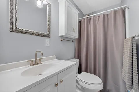 a bathroom with a sink a toilet a mirror and shower curtain