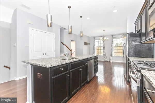 a kitchen with stainless steel appliances granite countertop a stove and a wooden floors
