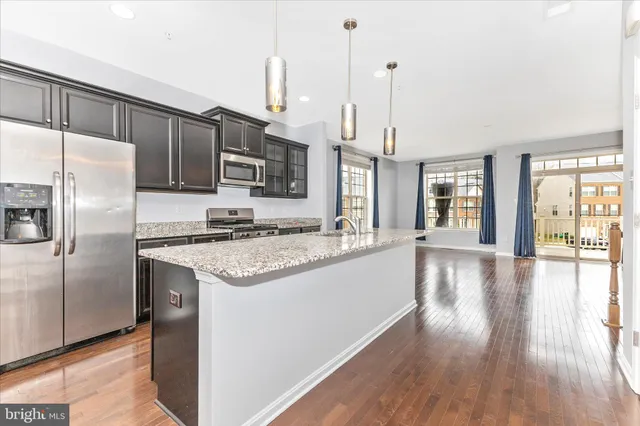 a kitchen with stainless steel appliances granite countertop a refrigerator a stove and a wooden floors